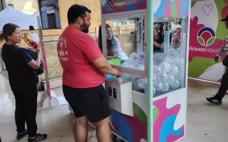 Peluchera de Arauco Estación cargada con esferas de premios y un participante jugando