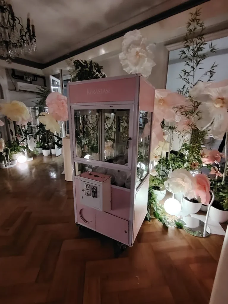 Peluchera Kérastase rosada ambientada con decoración floral en un evento de belleza