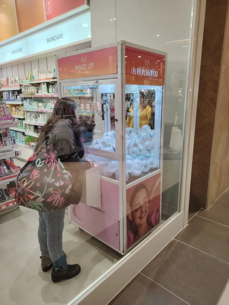 Clienta jugando en una peluchera personalizada instalada dentro de una tienda de maquillaje