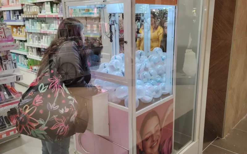 Clienta jugando en una peluchera personalizada instalada dentro de una tienda de maquillaje
